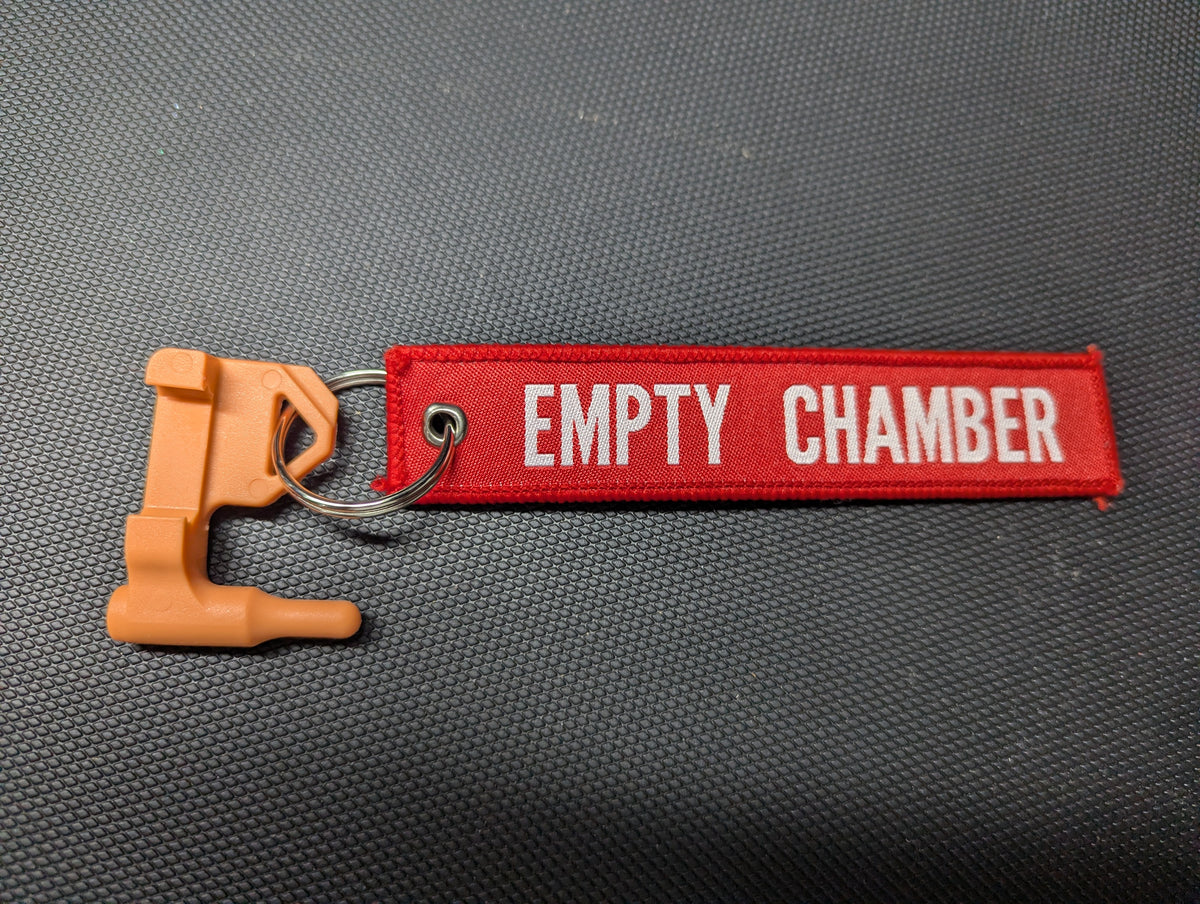 Red EMPTY CHAMBER keychain with bright orange chamber flag, photographed upright
