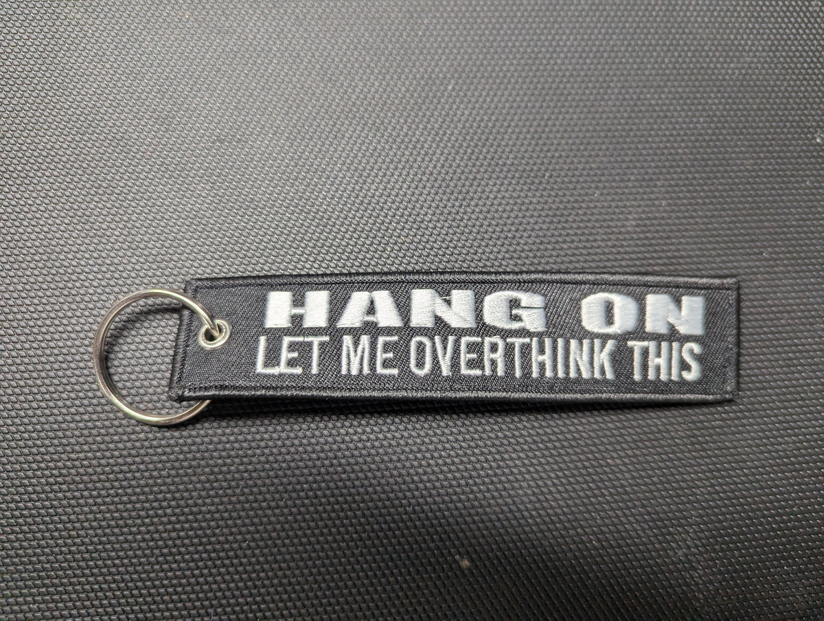 Black double-sided embroidered keychain reading Hang On, Let Me Overthink This, upright product photo